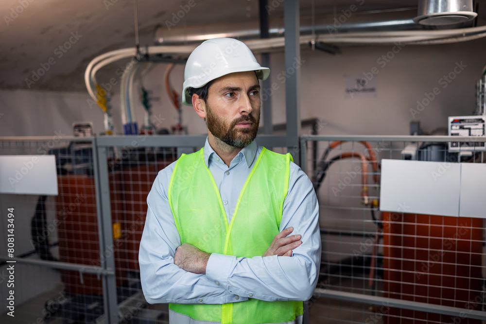 male engineer technician standing in technical room of electrical switchboard, wearing green safety vest, helmet in environment of electrical substation. male engineer technician standing in technical room of electrical switchboard, wearing green safety vest, helmet in environment of electrical substation.