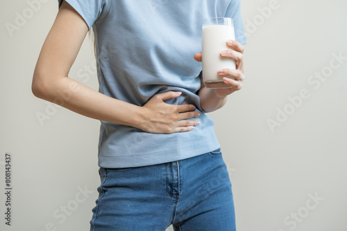 Pain, suffering asian young woman having a stomachache, abdominal pain or digestive, hand in holding belly after drink glass of milk. Lactose intolerance, allergy from dairy food, health care problem.