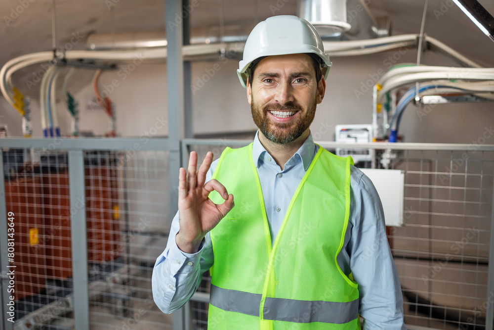 Handsome worker man wearing uniform and helmet smiling positive doing ok sign with hand and fingers. Successful expression. Handsome worker man wearing uniform and helmet smiling positive doing ok sign with hand and fingers. Successful expression.