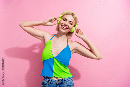Portrait of good mood adorable woman with bob hair wear colorful top touch headphones enjoy music isolated on pink color background