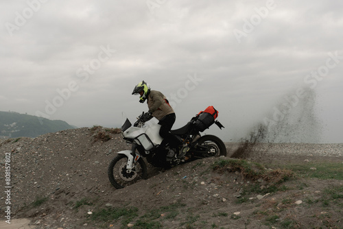 Motorcyclist traveling on adventure motorcycles on sea shore towing passing off-road on sand