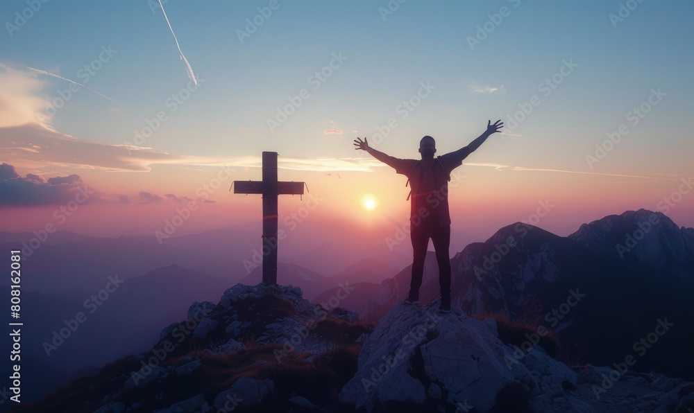 Silhouette of man with arms outstretched next to a cross on top of a mountain, sunset in the background, concept of faith, Christianity.