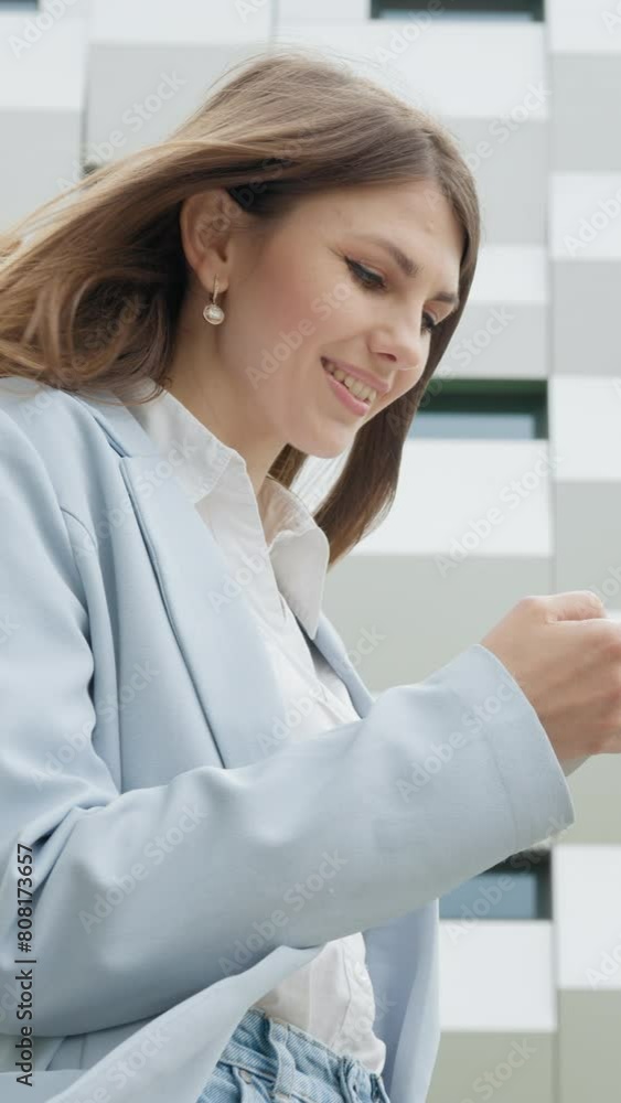 Vertical Screen: Business woman using smartphone texting female executive checking emails. Business. Social Network. Apps. Career people. Shooting on the street near the office. The girl looks at the Vertical Screen: Business woman using smartphone texting female executive checking emails. Business. Social Network. Apps. Career people. Shooting on the street near the office. The girl looks at the