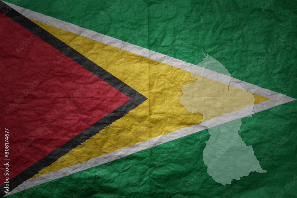 big national flag and map of guyana on a grunge old paper texture background