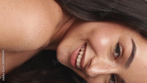 A detailed closeup captures a woman's smiling face, highlighting her clean skin and the concept of natural beauty and skincare.