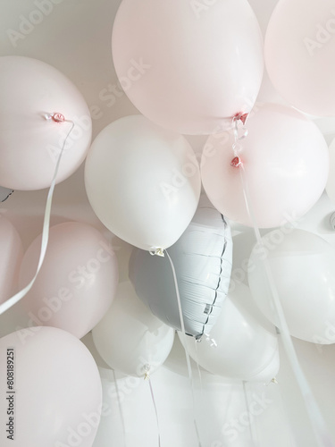 Pastel helium balloons hang from the ceiling in the room, holiday atmosphere