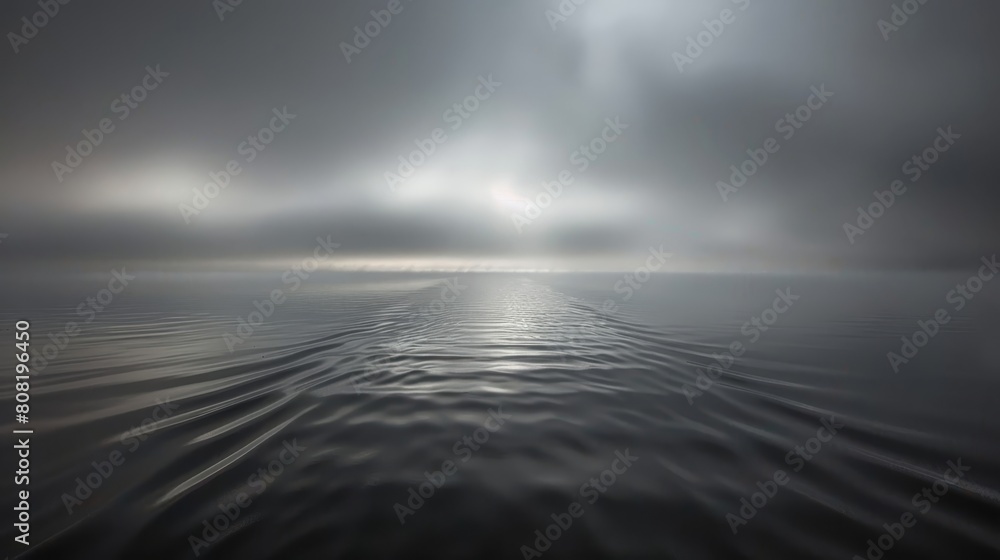  A large body of water with the sun shining through clouds, the sky serving as its backdrop