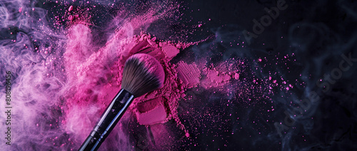 Makeup brush with pink powder explosion on black background, photo