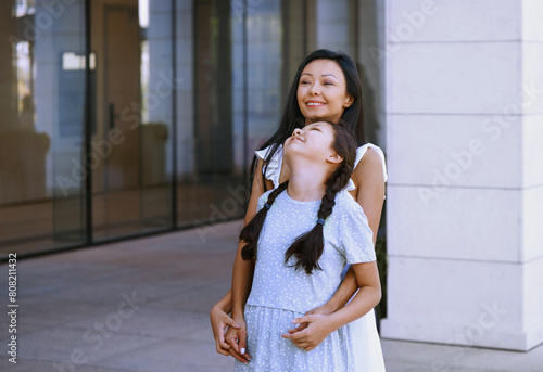 Girl with autism spectrum having fun with her mother while walking in the city photo