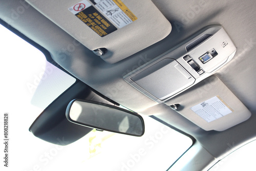 Close up interior view of the car roof or ceiling light panel. Car ceiling lamp, interior's details in modern car. Car headliner. Sun visor auto. Rearview mirror. 