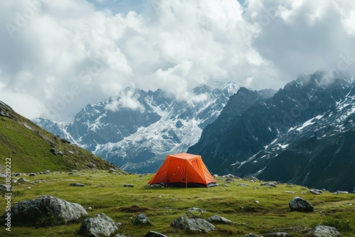 An orange tent stands alone amidst the vast beauty of a rugged mountain landscape © anatolir