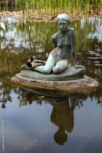 Statue of a sitting girl, with an actual duck at its side, in the waters of a pond in the Japanese Garden, Margaret Island