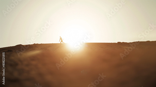 Silhouette of a person walking on a hilltop against the sunrise. photo