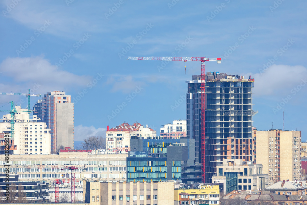 A building is being constructed using a tower crane on a summer day.
