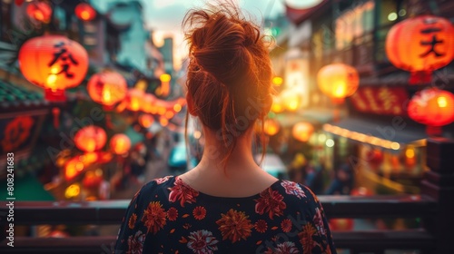  A woman stands before a city street at night Lanterns suspended above hang aglow Behind her, buildings loom in the darkness