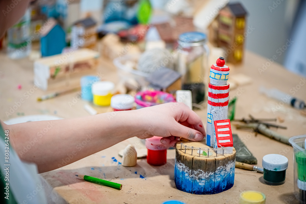 cute teen girl at a master class making a DIY wooden lighthouse made of ...