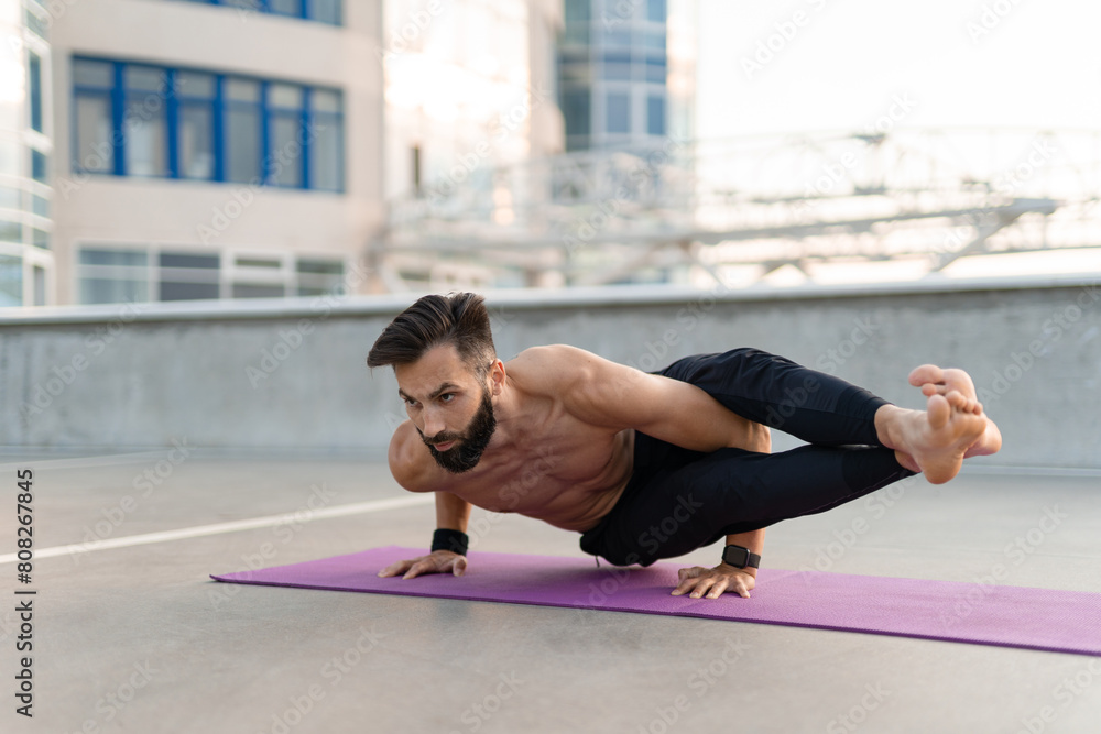 attractive hansome man with athletic strong body doing morning yoga asana outdoors