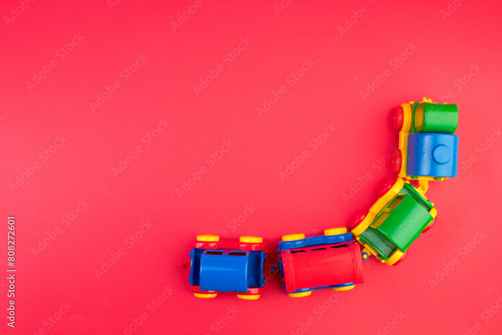 Obraz premium Children's toy, a multi-colored steam locomotive on a rede background.