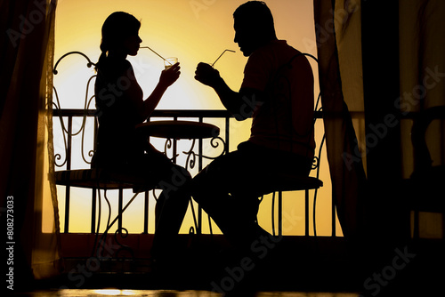 A Couple man and woman silhouette on a balcony by the sea on the background. Meeting in a double date on the terrace.