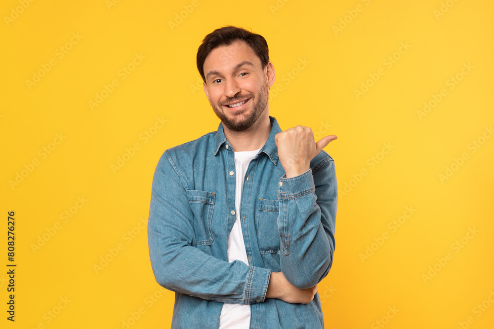 A man wearing a blue shirt is pointing at an unseen object or direction. He appears focused and engaged, perhaps indicating something significant or interesting, copy space A man wearing a blue shirt is pointing at an unseen object or direction. He appears focused and engaged, perhaps indicating something significant or interesting, copy space