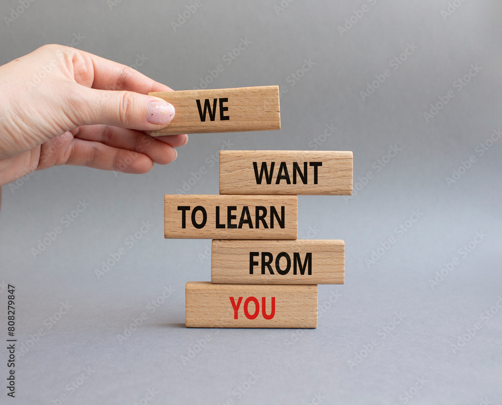 We want to learn from you symbol. Wooden blocks with words We want to learn from you. Beautiful grey background. Businessman hand. Business and We want to learn from you. Copy space.