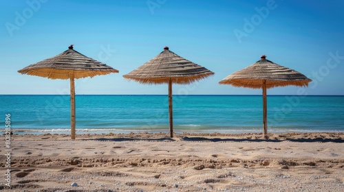 Photo of three straw beach umbrellas on the beach on Demand