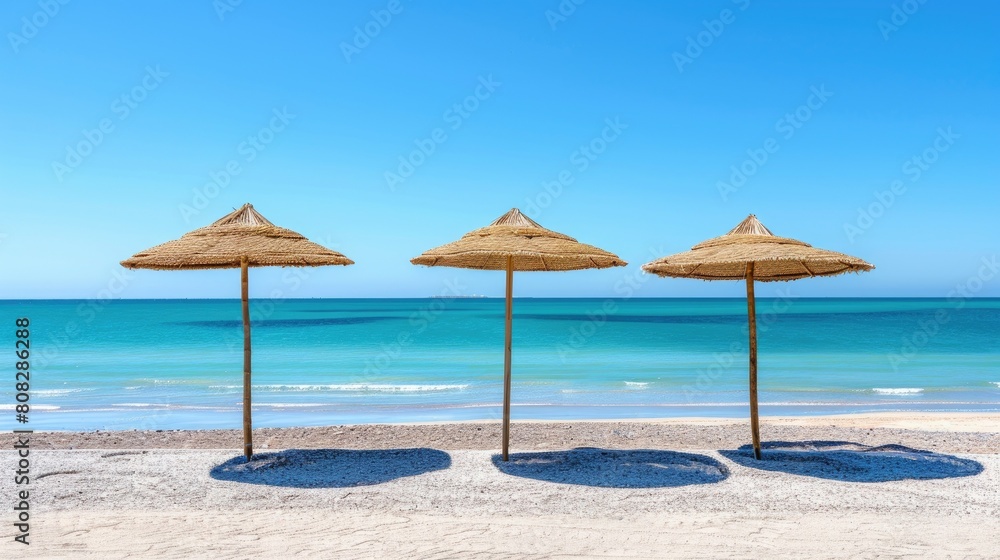 Photo of three straw beach umbrellas on the beach on Demand Photo of three straw beach umbrellas on the beach on Demand