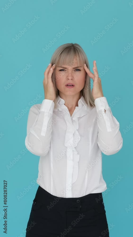 Unwell Caucasian businesswoman suffering from headache or migraine on blue background. Work related pressure and tension. Vertical video. Unwell Caucasian businesswoman suffering from headache or migraine on blue background. Work related pressure and tension. Vertical video.