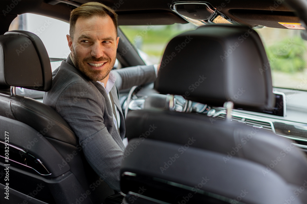 Welcoming smile from a joyful driver in a luxury sedan on a sunny day Welcoming smile from a joyful driver in a luxury sedan on a sunny day