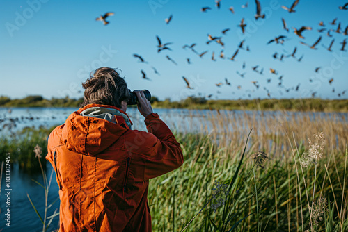 enthusiast birdwatching in marshlands with binoculars photo