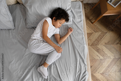 Quadro em tela African American young child with curly hair is taking a nap, curled up on a nea