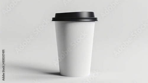 A white coffee cup with black lid on a gray background.