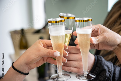 Champange flutes filled with bubbly are held by female hands as a toast is made to the celebration