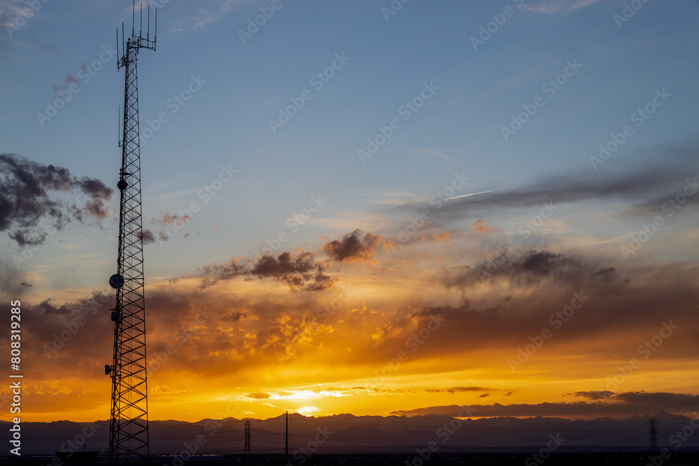 Sunset sky in the spring over the suburban neighborhood in Aurora, Colorado, with a communication tower in the foreground Sunset sky in the spring over the suburban neighborhood in Aurora, Colorado, with a communication tower in the foreground