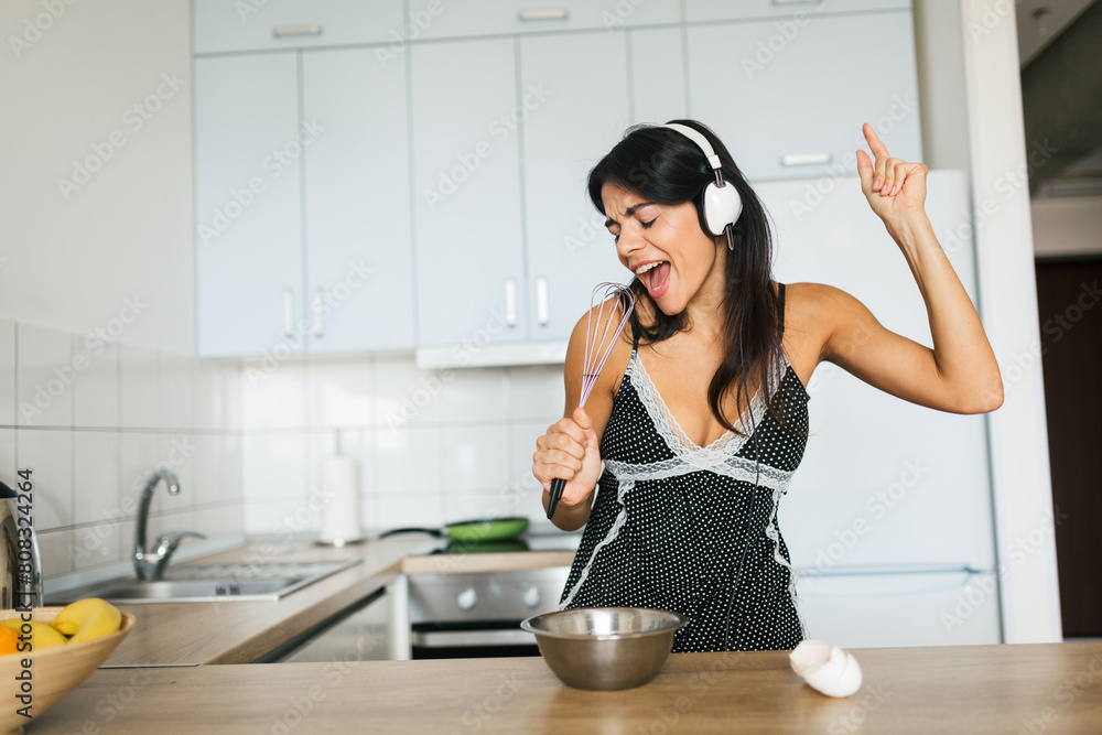 attractive smiling woman in pajamas having breakfast in kitchen