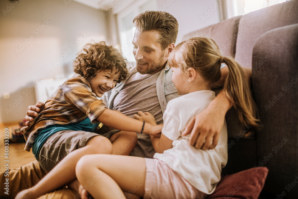 Happy father playing with son and daughter at home