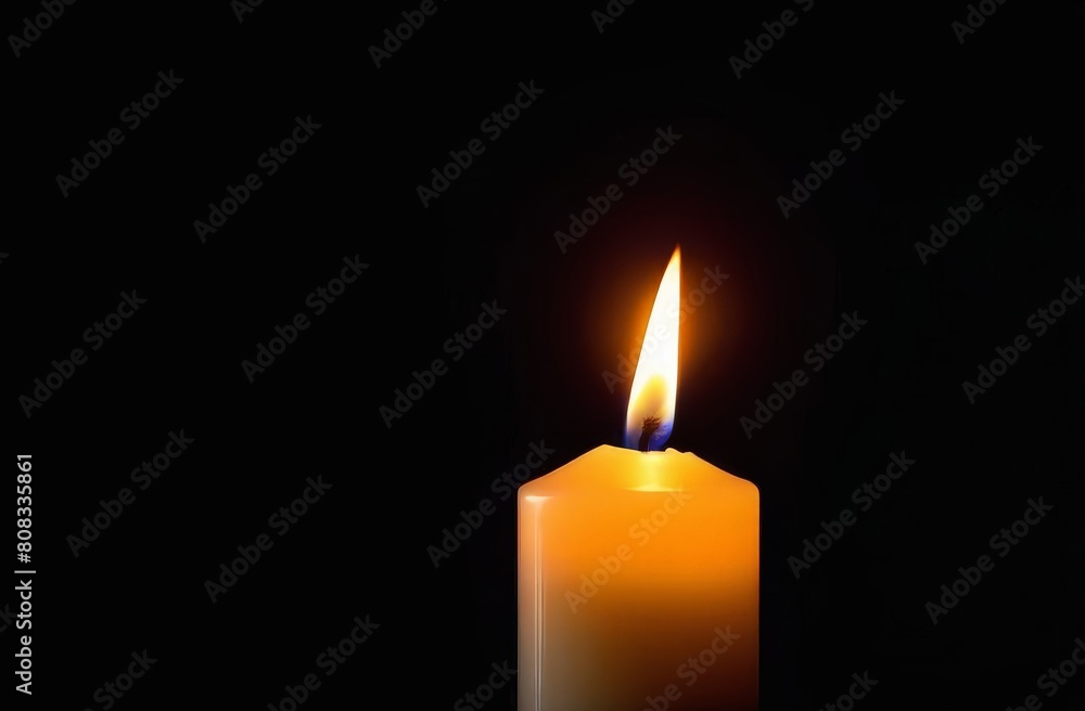 Candle burns on a dark black background, close-up