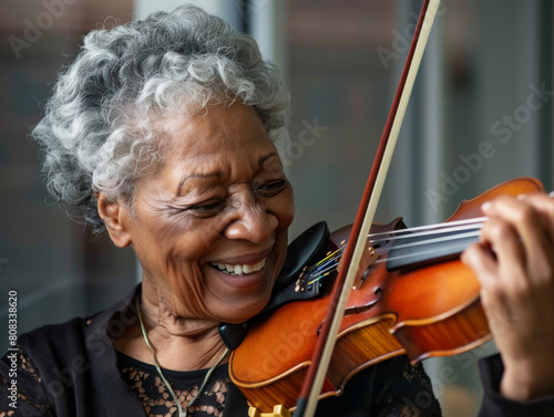 Closeup portrait os a senior black woman playing the violin with a smile.  Shallow dof.