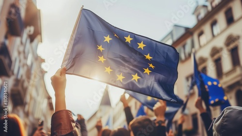 Big flag of European Union waves during public demonstration in Polish city to support democracy and Polish membership in EU, crowd of people in soft focus photo