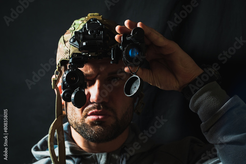 Portrait of a military man with a beard with a binocular night vision device on his head. Soft focus photo.