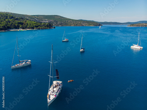 Scenic aerial view many yachts boats moored at Croatian bay harbor shore blue turquoise clear water at bright summer sunny day. Top above Mediterranean sea marina. Boat vessel charter service