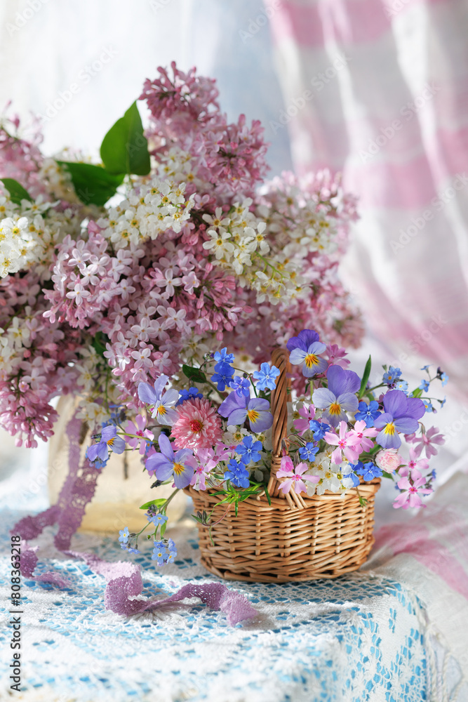 Φωτογραφία Spring still life with flowers, a bouquet of blooming lilacs and bird cherry in a vase, a basket with pansies, forget-me-nots and phlox, a beautiful postcard