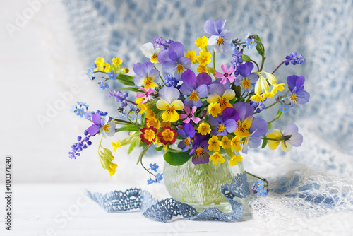 Spring still life with flowers, bouquet with pansies, forget-me-nots, primroses, forget-me-nots, muscari and phlox in a vase on the table, a beautiful postcard.