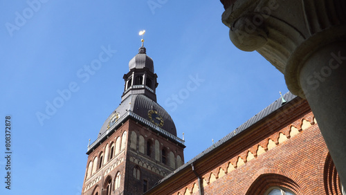 The Riga Cathedral building has a scenic view of the central tower of the Riga Dome church architecture and a gilded rooster at the top - a famous historical landmark of Latvia's capital.