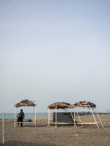A man relaxes on the beach in a sun lounger with a thatched roof. Resort on the Black Sea.