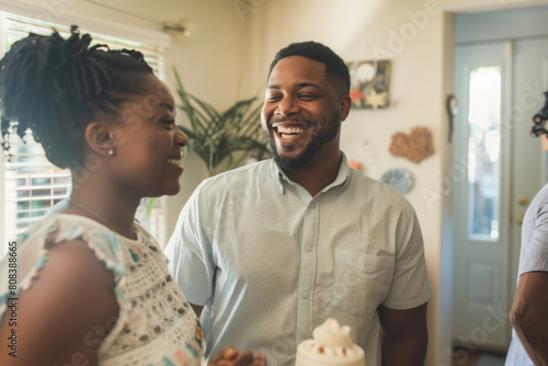 Joyous moment as a young African American couple celebrates with friends, sharing laughter and cake in a cozy home setting.