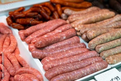 Different types of meat sausages laid out on counter in butcher shop..