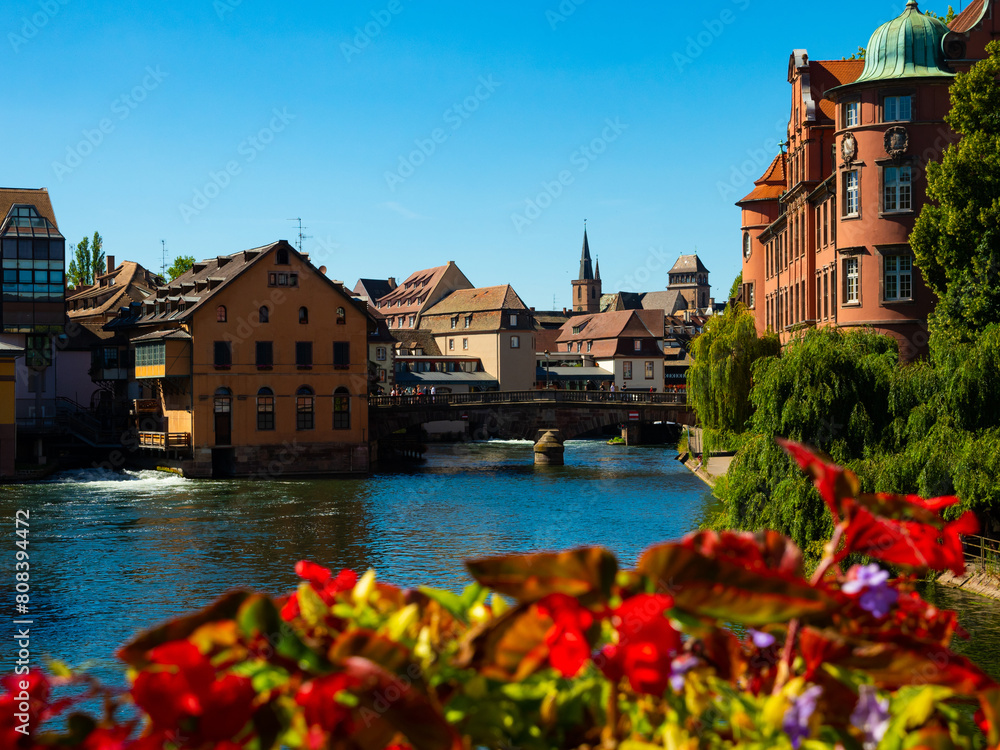 Peaceful cityscape of Strasbourg during summertime. Streets and canals of French city decorated with colorful flowers.