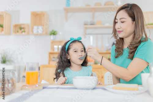 Asian children and her mom have a breakfast in the morning, child nutrition and development, they feeling happy in family time