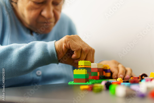 An older woman is assembling constructions with plastic blocks